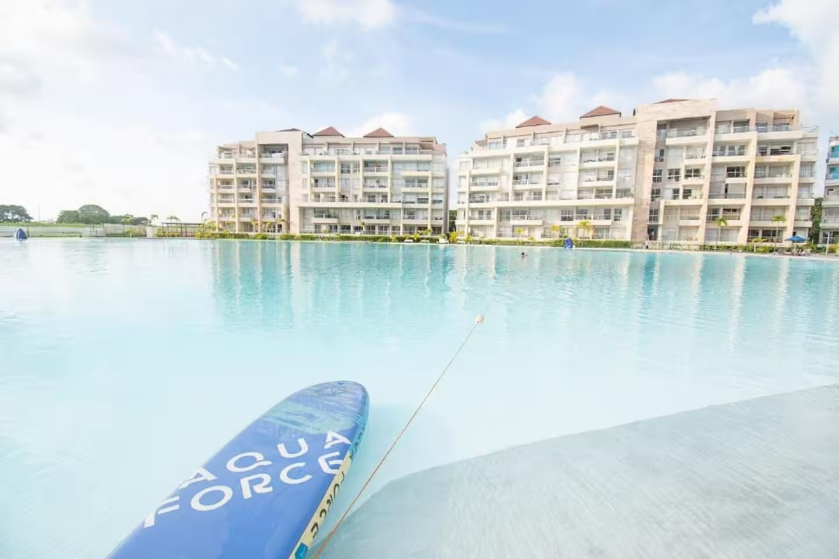 Piscina estilo laguna tipo resort con vistas abiertas al agua y a los edificios de apartamentos, aportando un agradable espacio exterior a tu estancia costera.