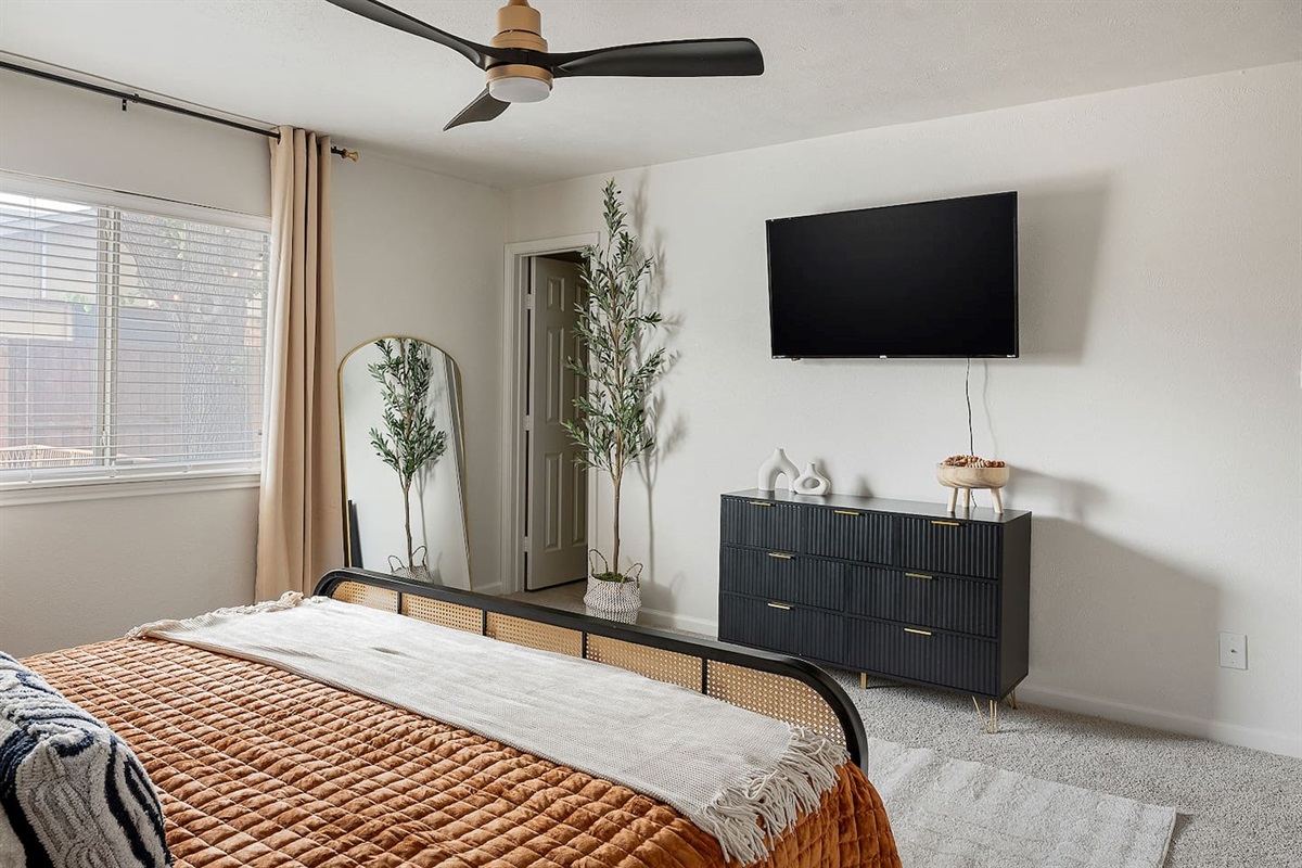 Indulge in the comfort of this spacious bedroom with a mounted TV and elegant dresser. The room is designed for both relaxation and convenience.