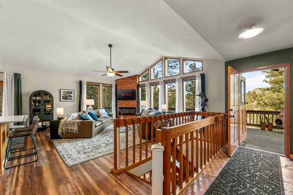🌄✨ Open-concept main level with soaring windows, cozy living room seating 🛋️, bar nook 🍸, and direct deck access—made for sunrise coffee and mountain-view hangs 🌲