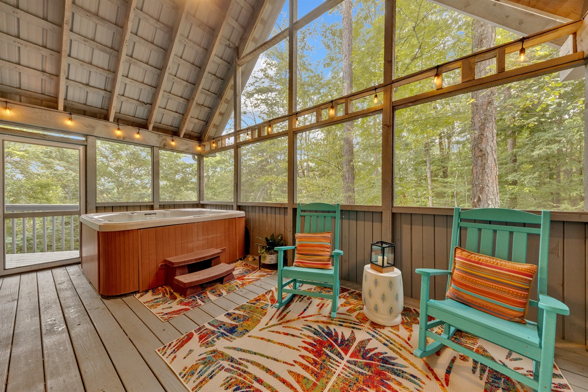 Relax in the private screened-in porch featuring a bubbling hot tub and comfortable rocking chairs