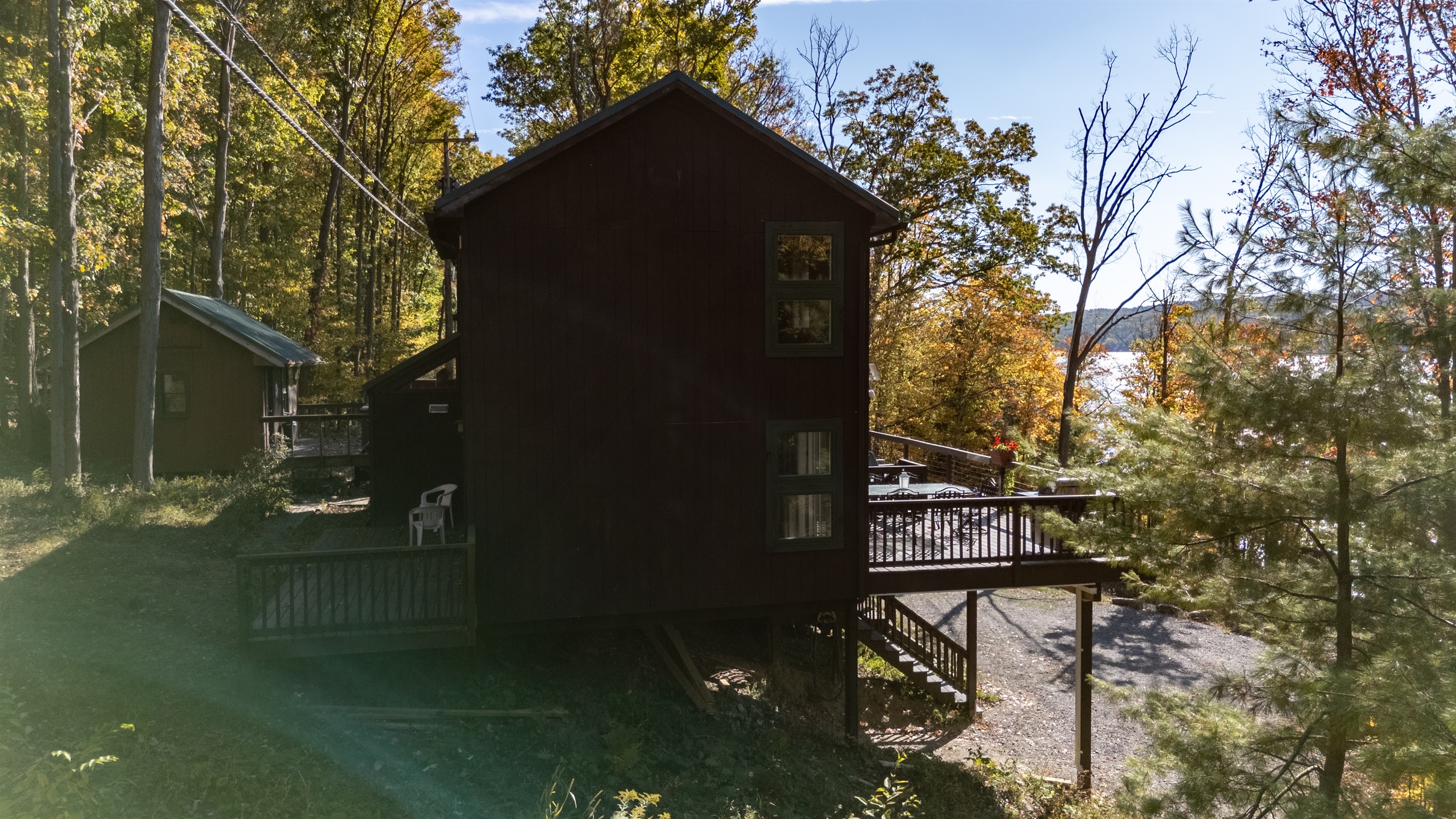 Night/darker exterior view of cabin amid trees — serene woodland vibe.