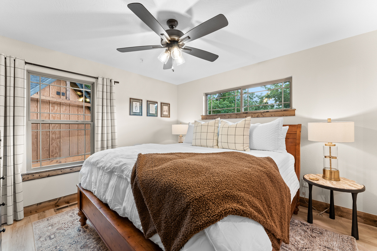 Twin nightstand lamps and a windowpane-pillow king framed by Ozark treetops.