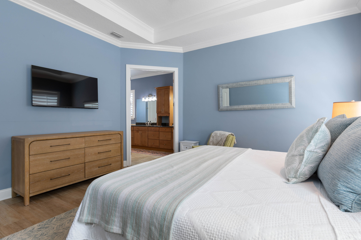 A wide dresser for unpacking and a wall-mounted TV for winding down, with the Primary ensuite just through the doorway.