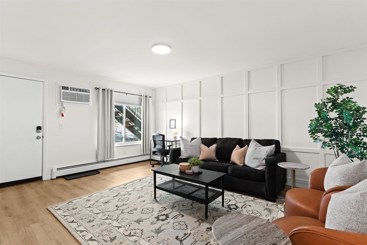 Spacious, stylish living room with cozy seating, chic décor, and a dedicated workspace—perfect for relaxing or working remotely.