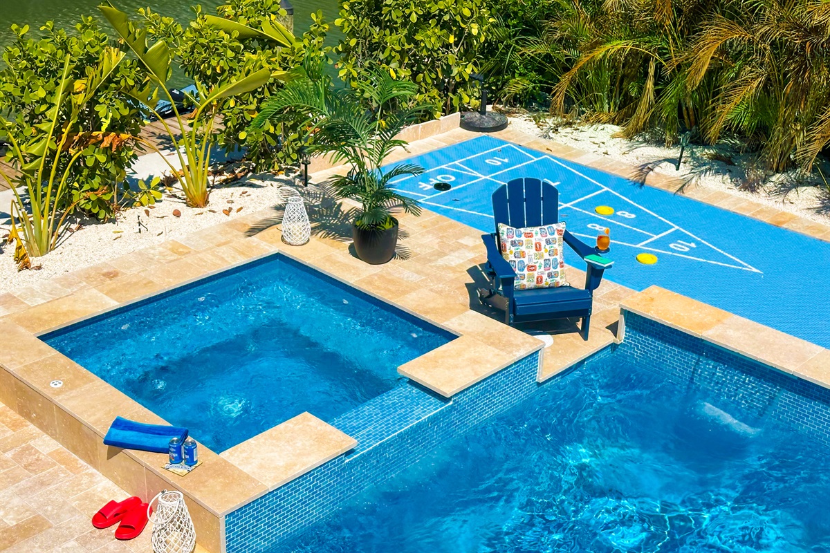 A backyard oasis with a pool and a spa and a shuffleboard court.