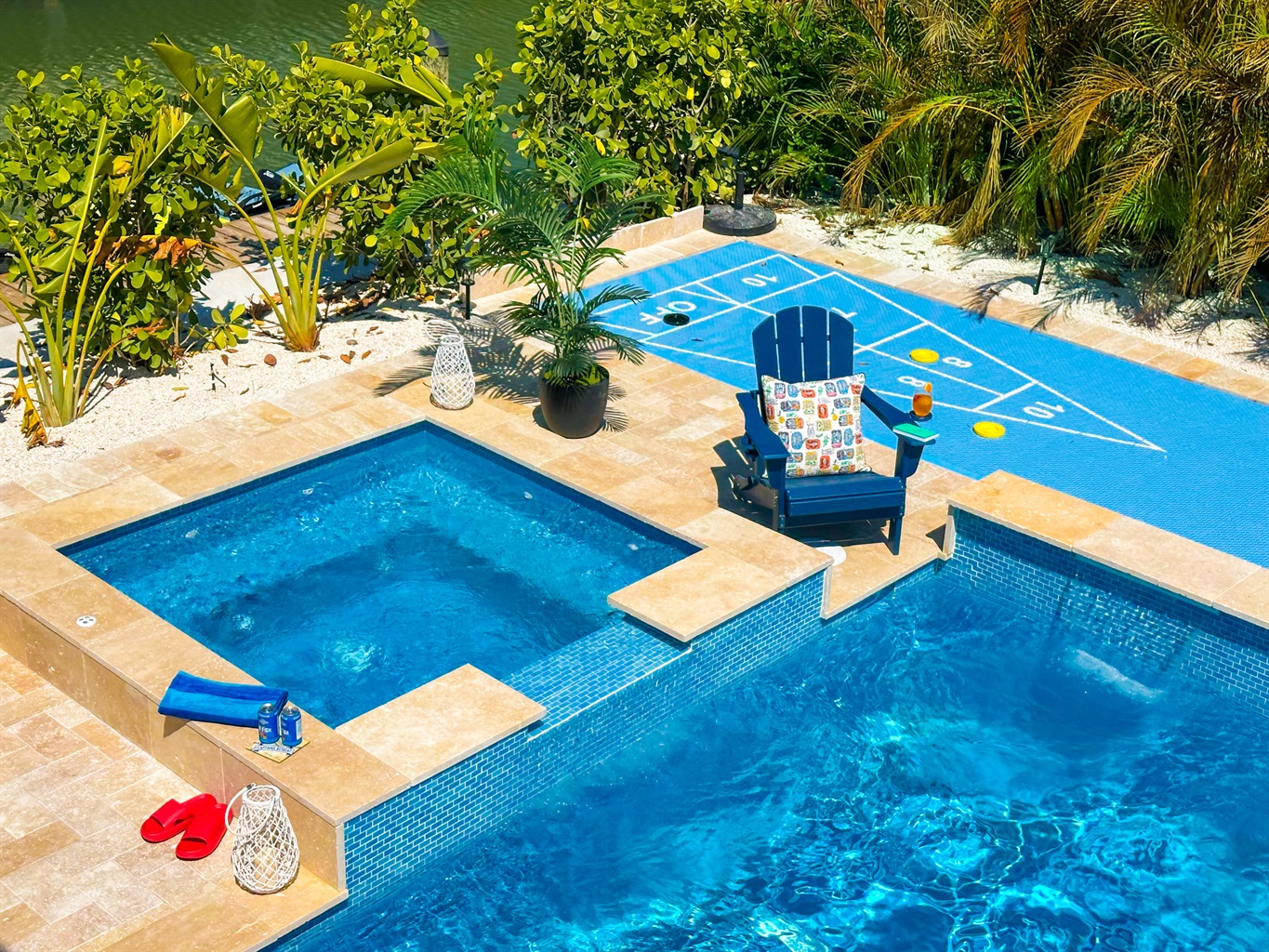 A backyard oasis with a pool and a spa and a shuffleboard court.