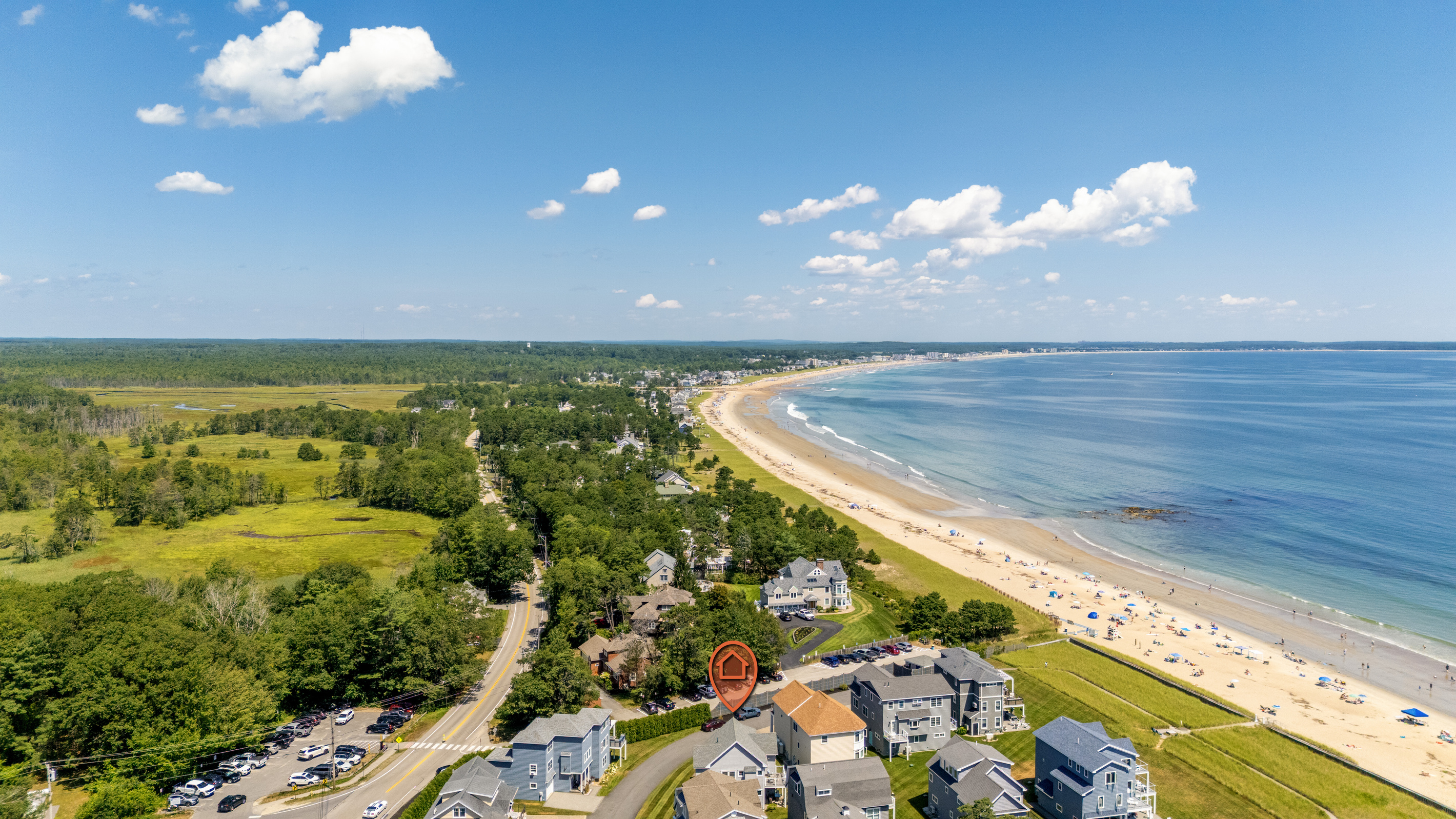A breathtaking aerial view highlights the home's location near a long stretch of sandy beach and ocean.