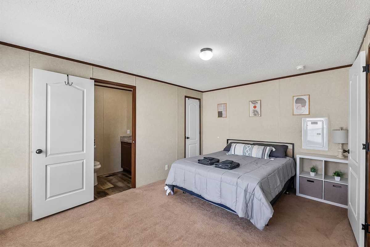 Bright and cozy bedroom featuring a plush queen bed, minimalist décor, and direct access to a private bathroom.