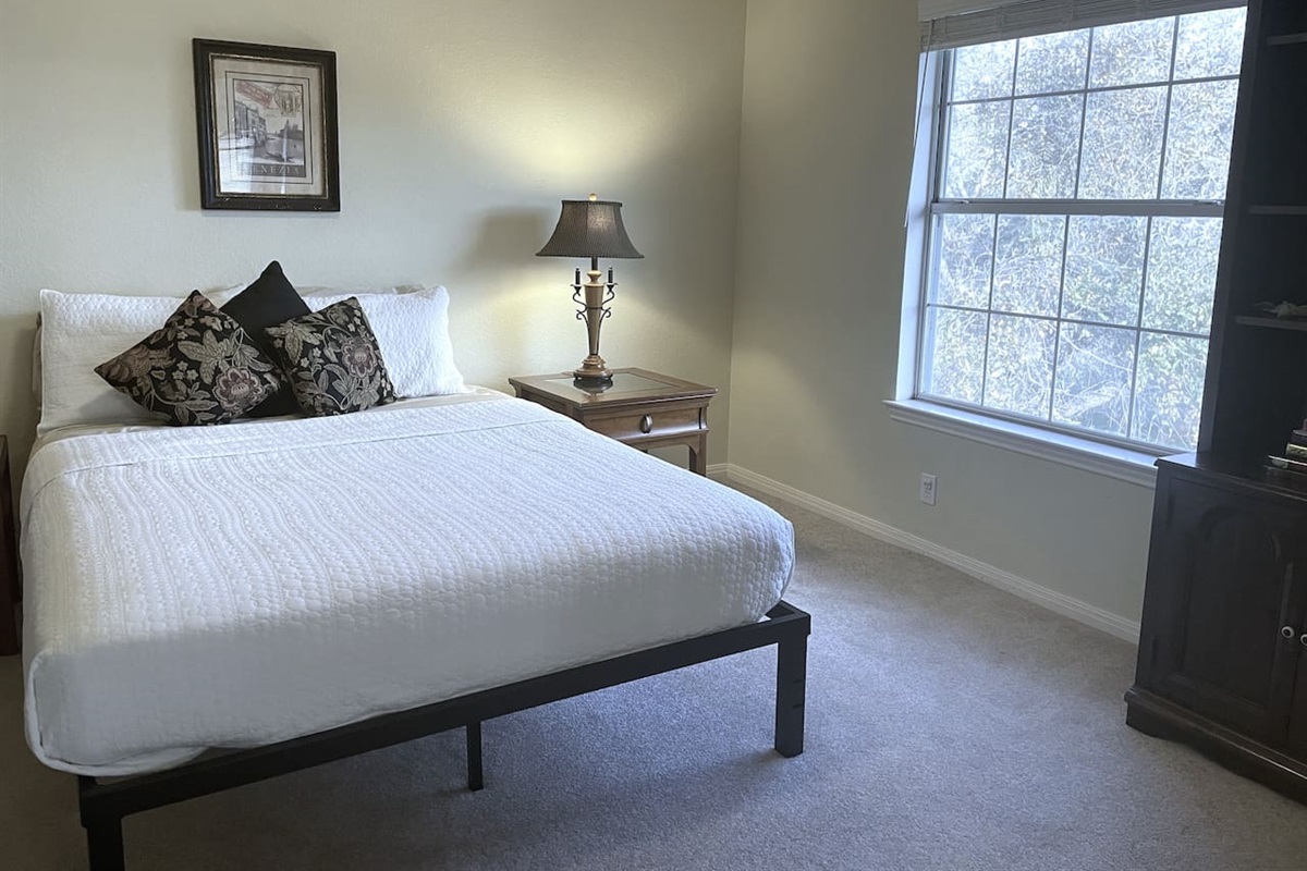 One of five private bedrooms, 'Room With A View' features queen sleeping, bedside charging stations, hanging and drawer space for clothing,  and an expansive treetop view.