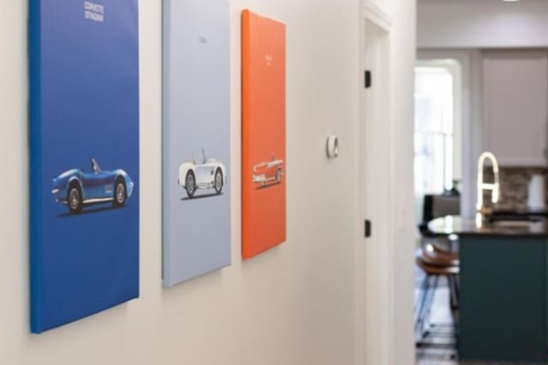 Stylish hallway with vibrant car-themed artwork, leading to a modern kitchen and cozy living space. 