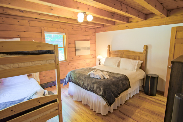 Offering a full size bed and a set of twin bunk beds, this second guest bedroom is perfect for a family, blending coziness and luxurious feel