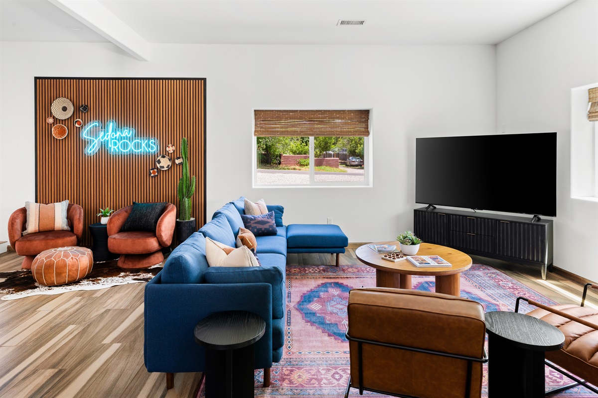 Open, tall ceilings complement the cozy sofa and chairs in this spacious living area, featuring a 75" Smart TV and Southwestern decor.