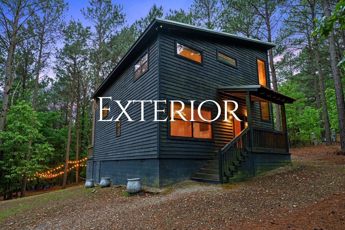 The cabin’s exterior showcases a clean, modern rustic design that fits perfectly into the wooded surroundings.