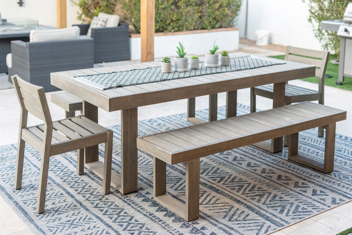 Close-up of the rustic outdoor dining table, set on a patterned rug and styled with succulents for laid-back elegance.