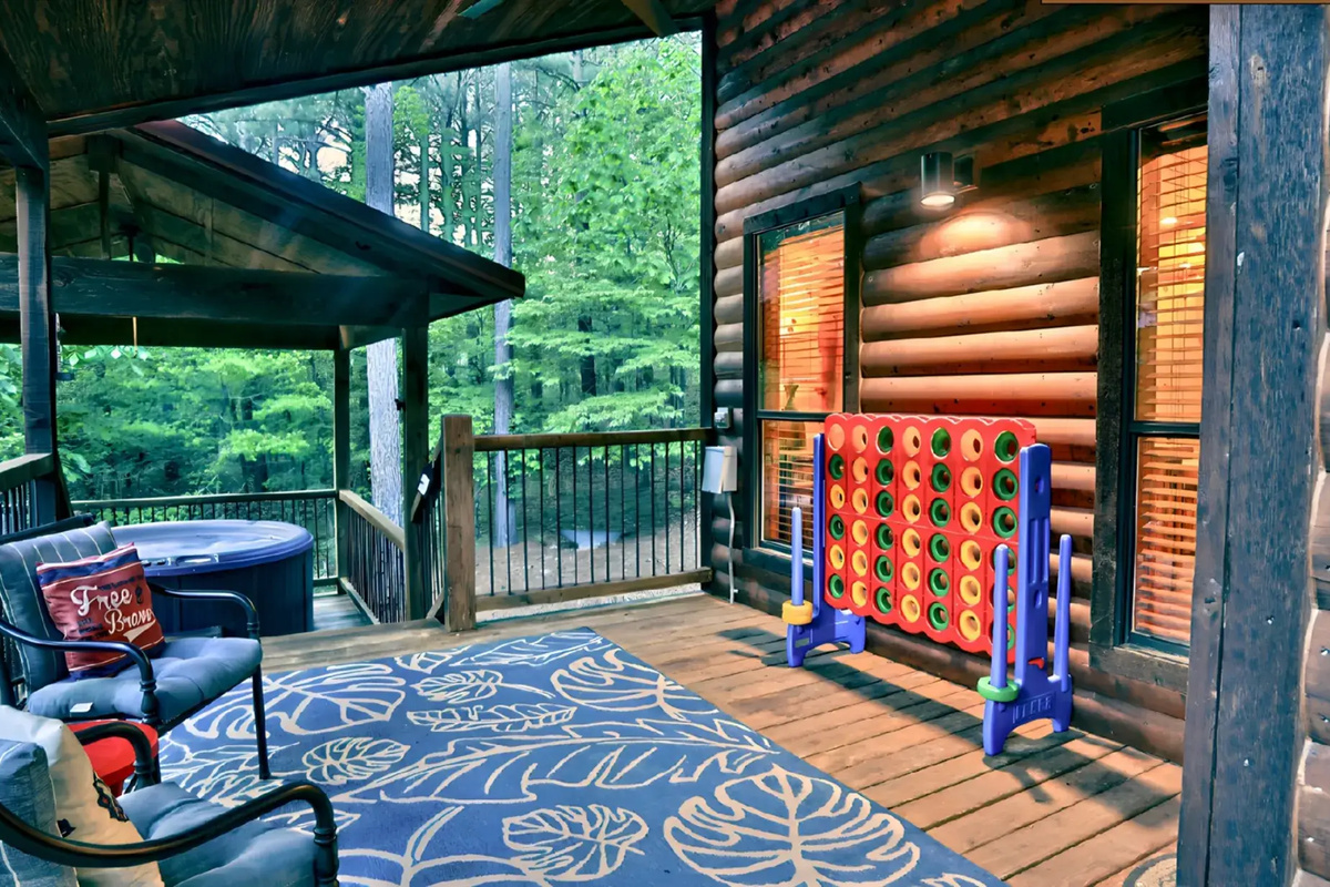 Spacious Porch: Enjoy scenic views, a relaxing hot tub, and fun games under the trees!