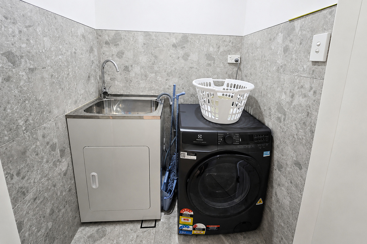 The washer dryer sits directly beside the sink, keeping the laundry setup easy to access and use.