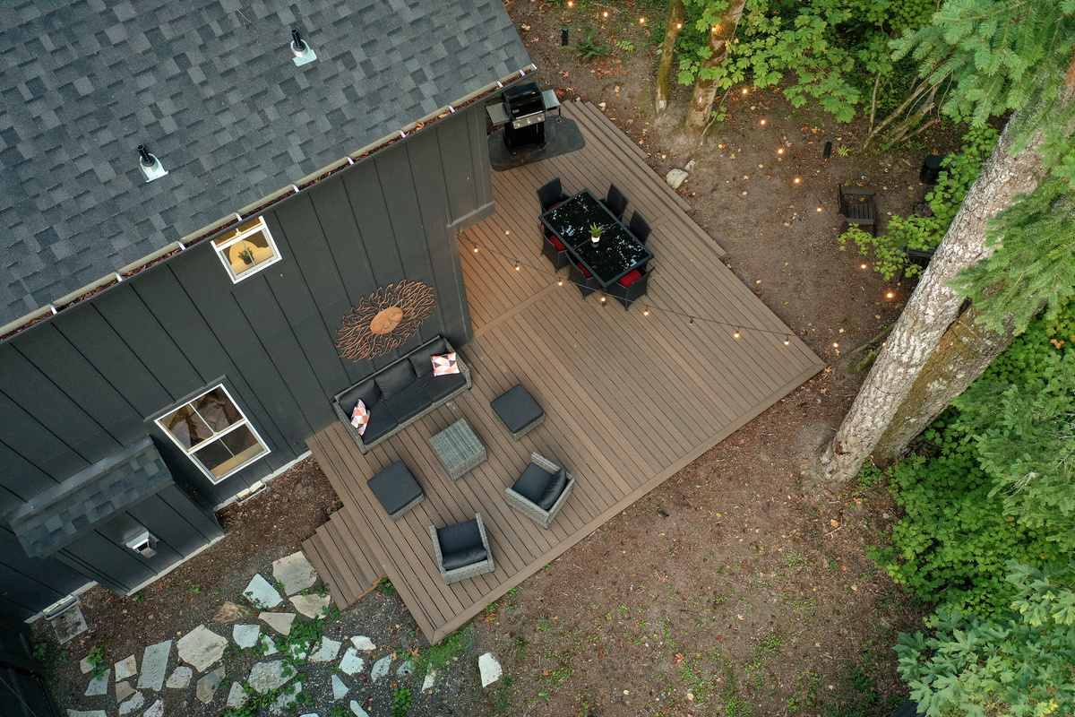 Dinner under the string lights: an aerial look at the deck, dining table, and grill tucked into the Mt. Hood forest.