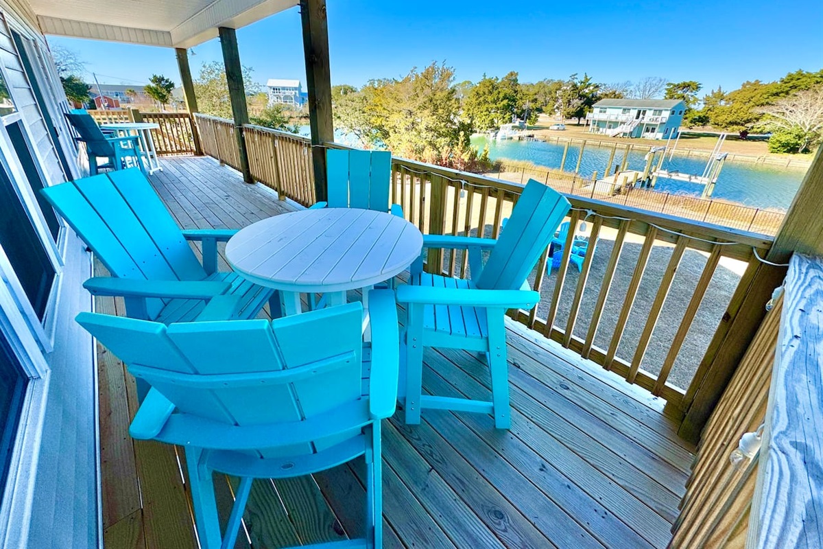 Private backyard dock with boat lift and fillet table, fenced-in backyard, fire pit with Adirondack chairs, hammocks, propane grill, picnic table, outdoor shower, expansive waterfront back deck with string lights, neighborhood boat ramp