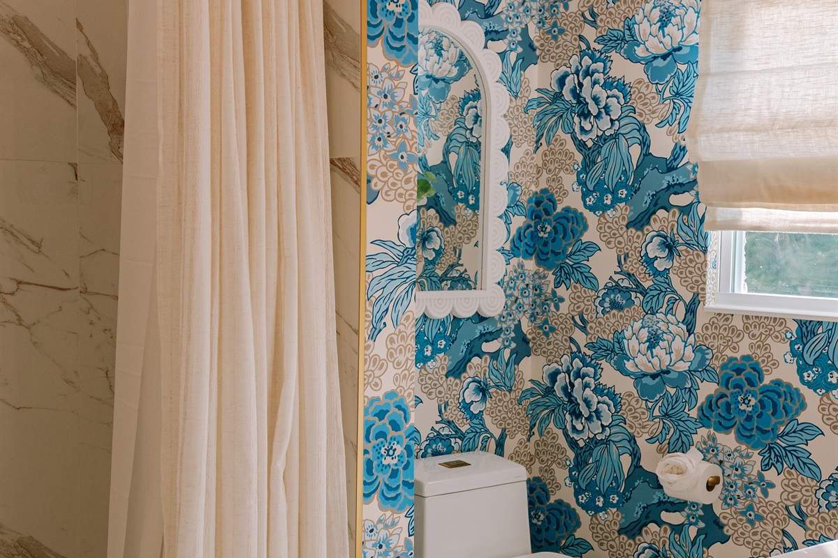 The shared full bathroom delights with colorful wallpaper and impeccable finishes.