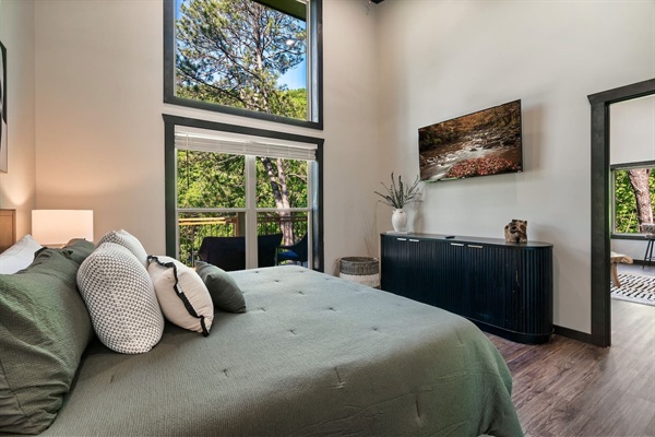 Bright king bedroom with soaring ceilings, Smart TV, and private deck access.
