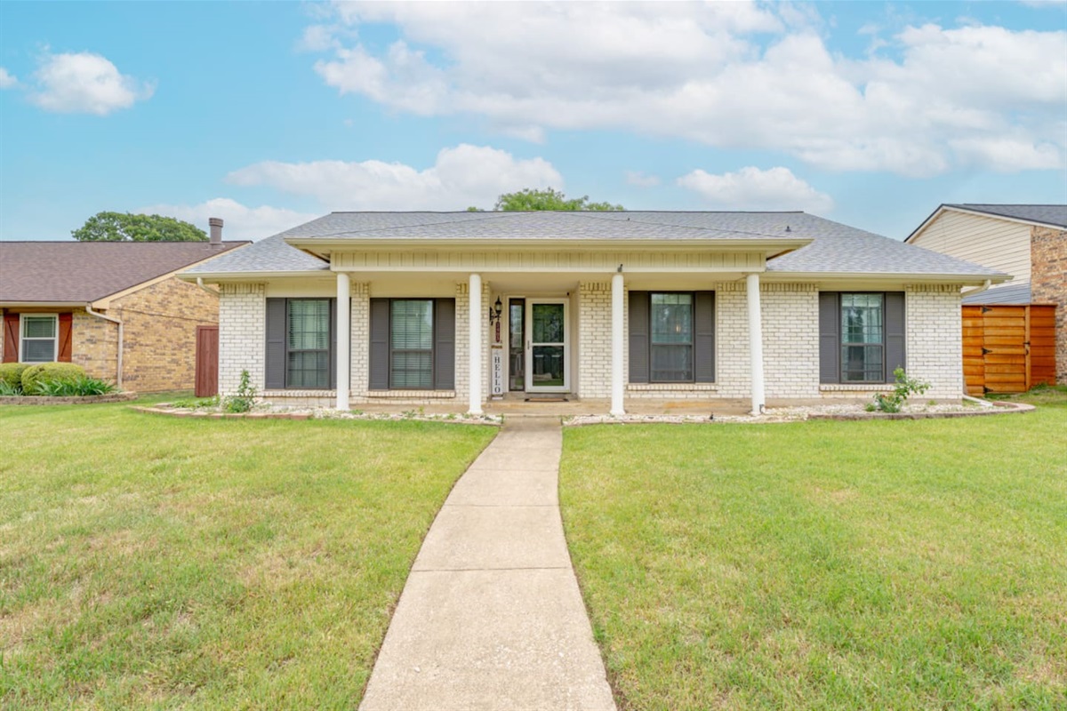 Welcoming curb appeal with manicured lawn and covered entry.