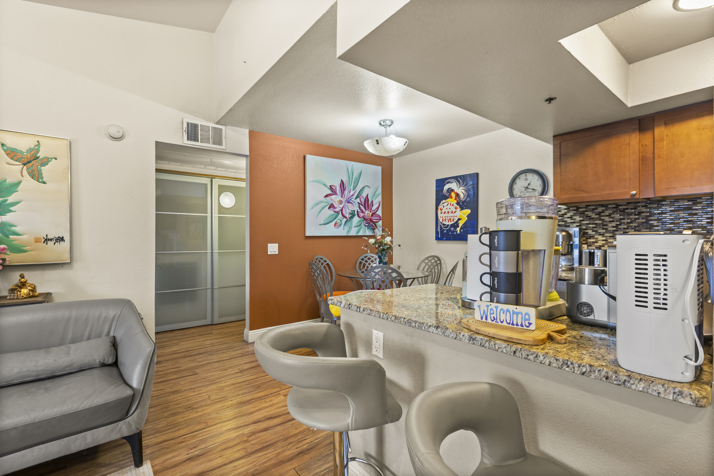 Kitchen bar with two stools, drink station, and the dining and living spaces connected nearby.
