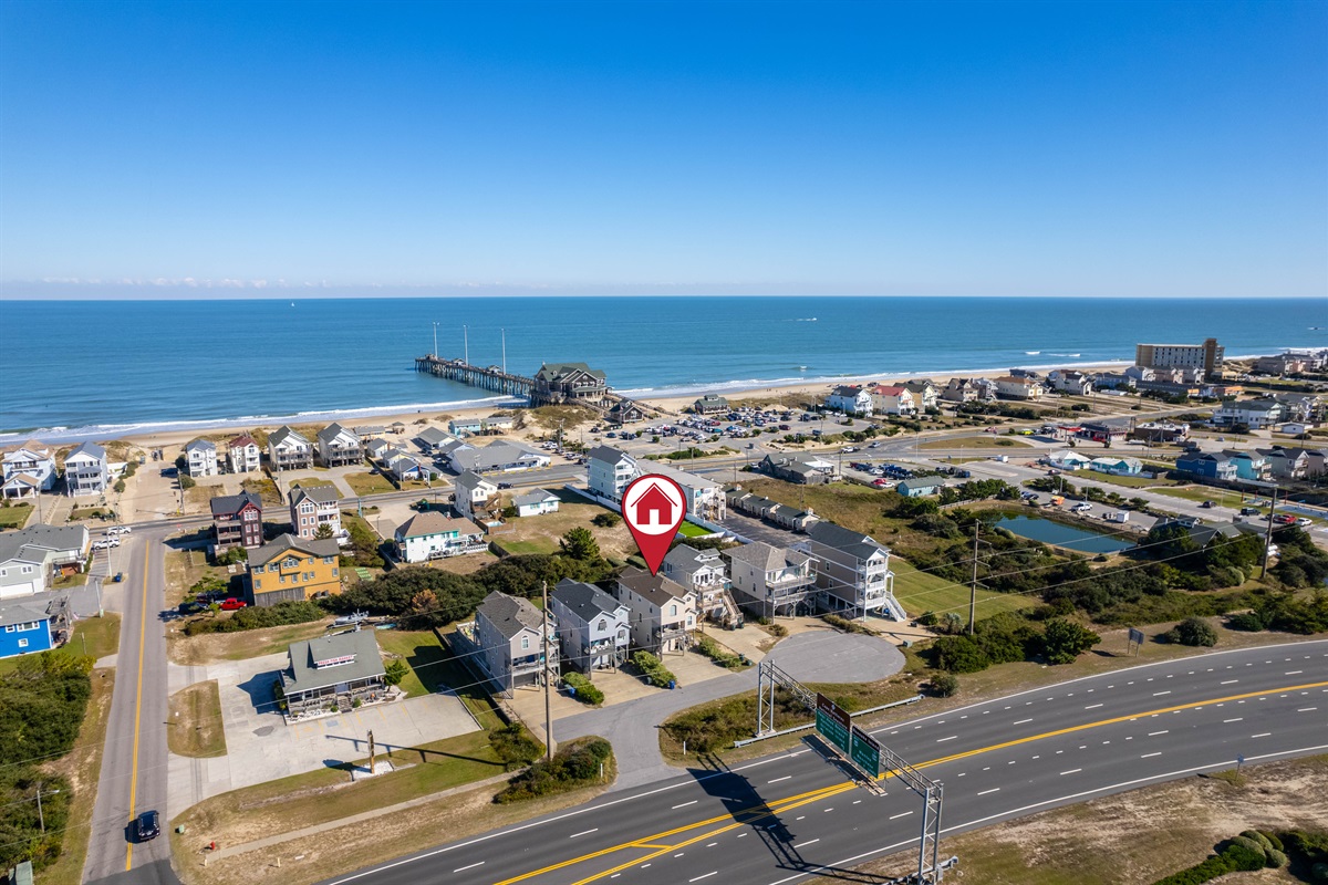 Wide-angle aerial capturing the home in context with the beach, pier, and surrounding neighborhood—perfect for showcasing proximity to local attractions.