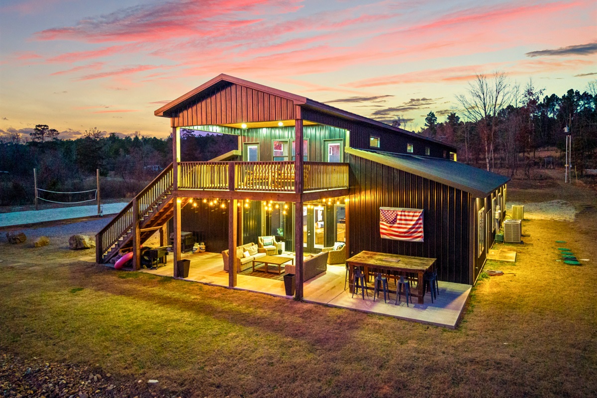 The illuminated exterior at sunset makes a striking first impression, blending modern design with rustic charm.