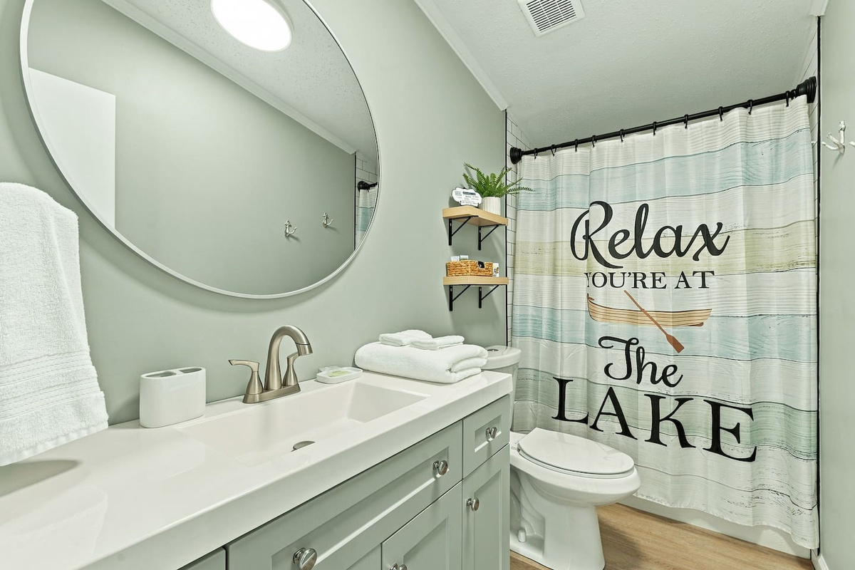 Full guest bathroom with a tub/shower combo, spacious vanity, fresh towels, and convenient storage—perfect for rinsing off and getting ready after a day on the lake.