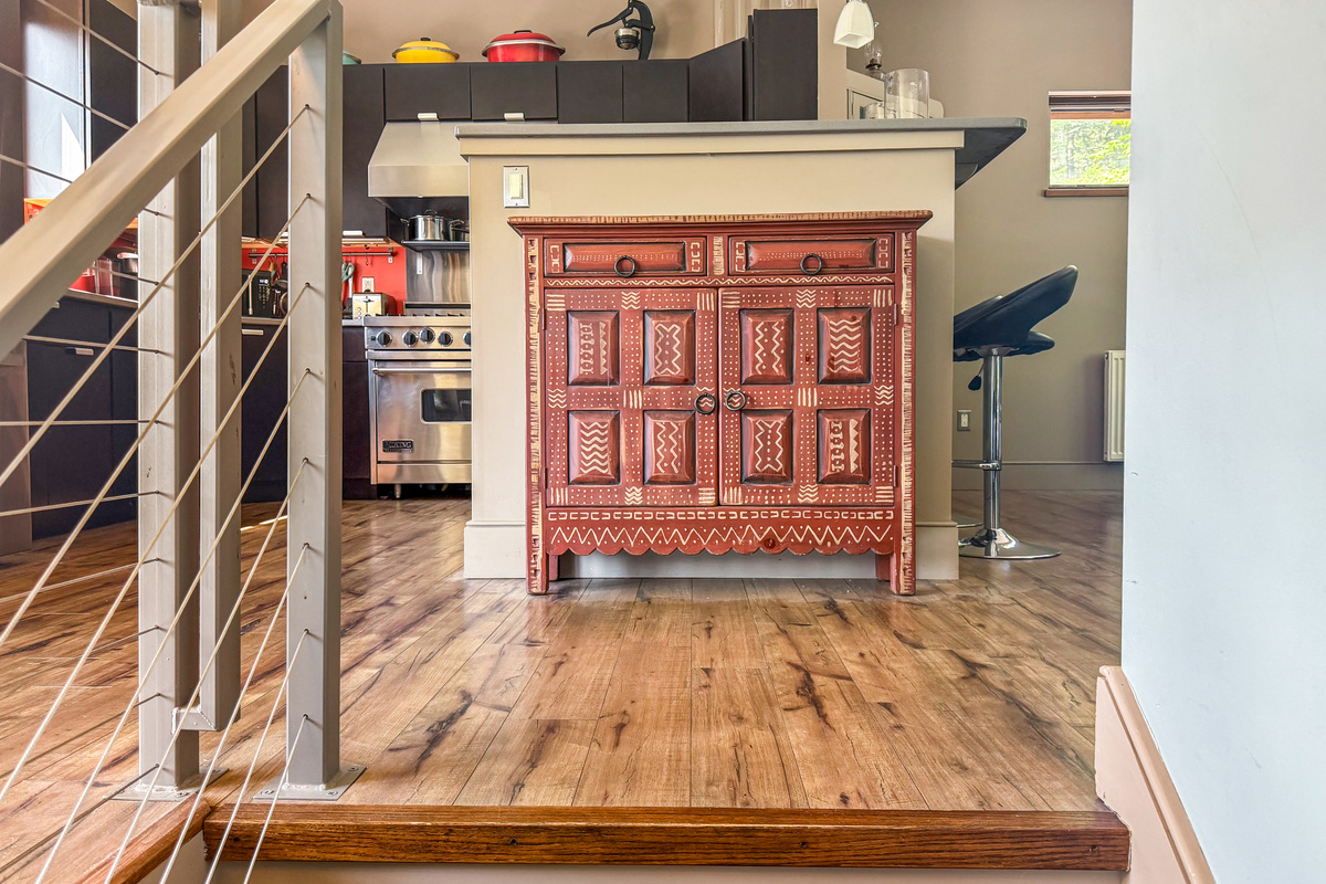 Modern cable-railing stairway leads to the main level social hub. This bright landing features curated designer furniture and offers a first glimpse into the open-concept living, dining, and kitchen areas at the heart of The Crag.