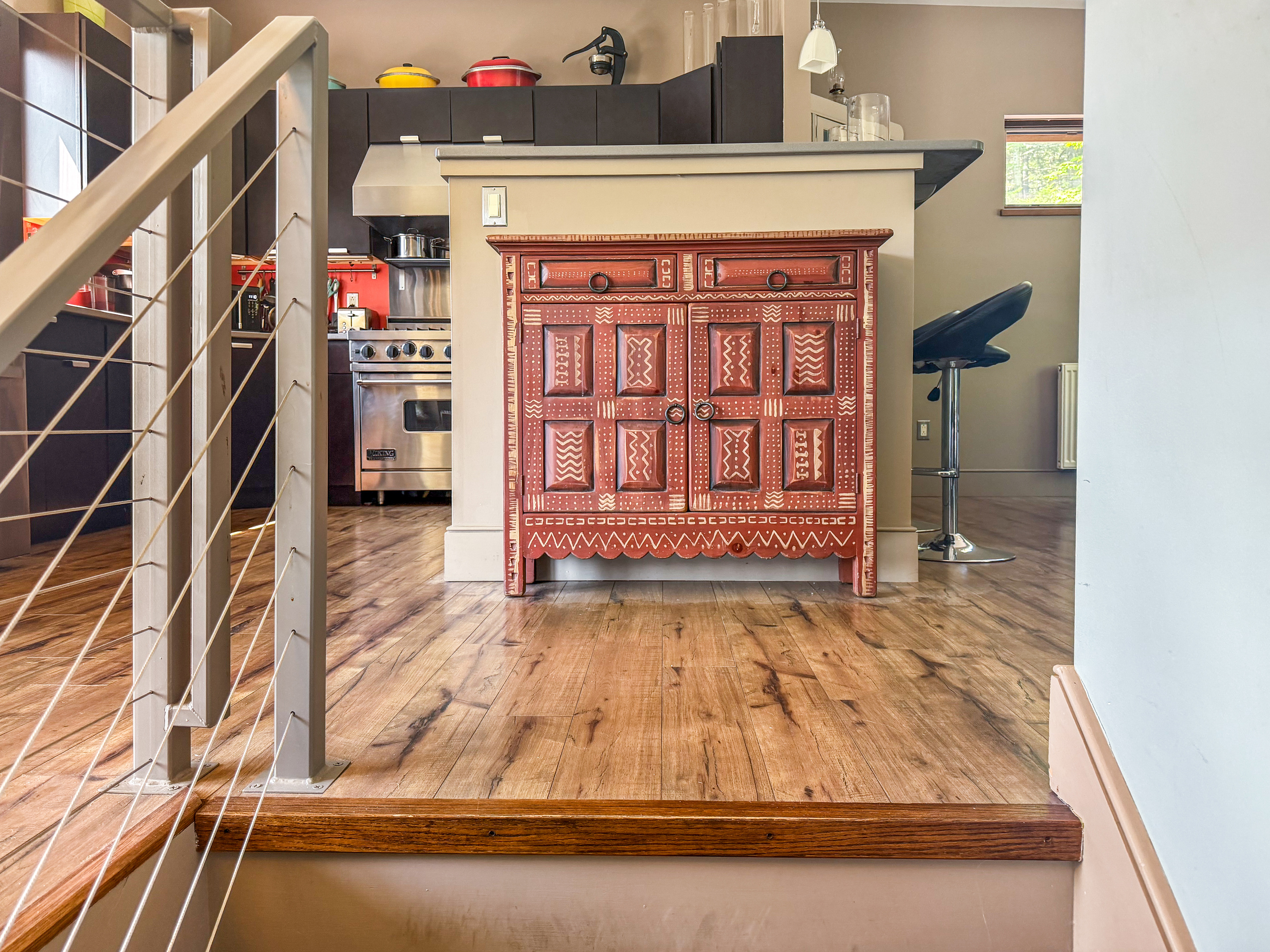 Modern cable-railing stairway leads to the main level social hub. This bright landing features curated designer furniture and offers a first glimpse into the open-concept living, dining, and kitchen areas at the heart of The Crag.