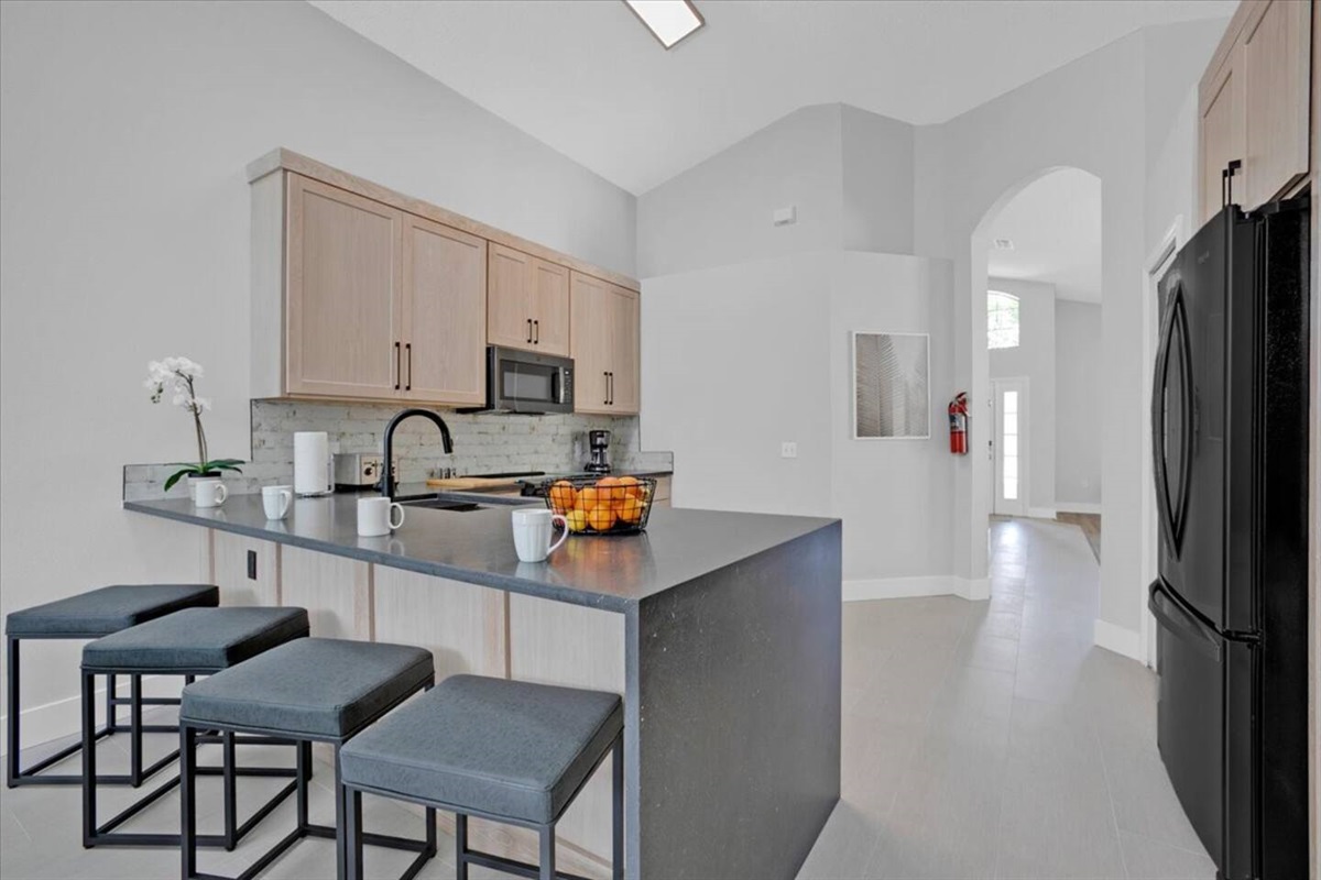 The kitchen has bar table with 4 bar stools
