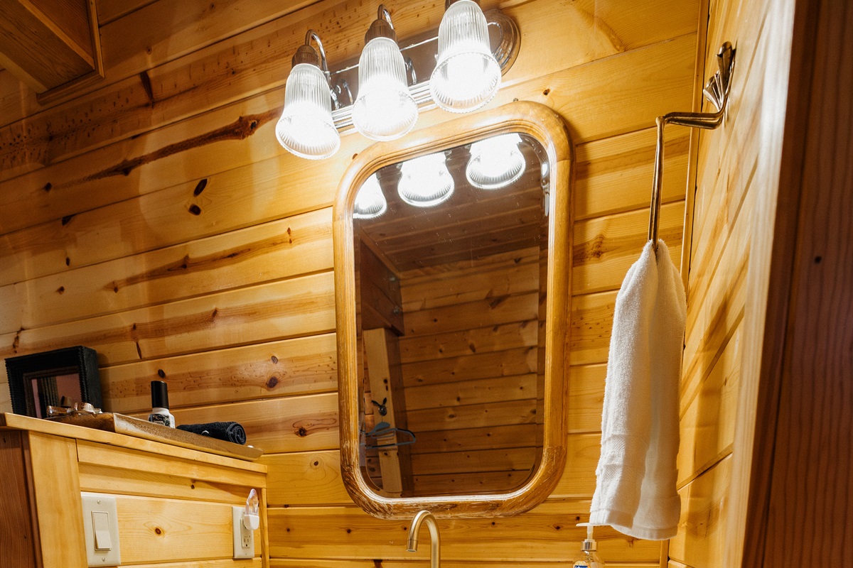 Poppywood Pines’ bathroom offers ample counter space and generous storage, featuring a stylish vanity, warm wood accents, and thoughtful design—perfect for getting ready comfortably during your relaxing White Mountains cabin stay.