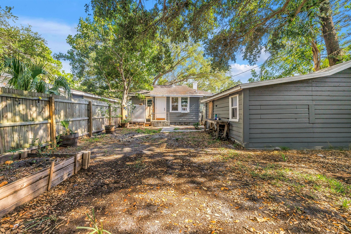 Spacious fenced backyard with mature trees, raised garden beds, and plenty of outdoor space to relax or enjoy the fresh air.