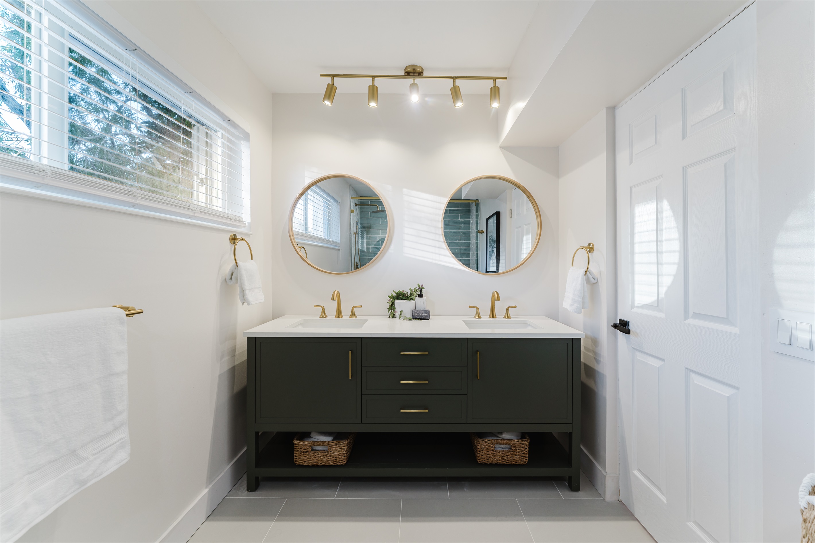 Spa-inspired ensuite with a walk-in glass shower, soft sage tile, and brushed brass fixtures. A double vanity with designer mirrors creates a bright, hotel-style retreat made for slow mornings and effortless luxury.