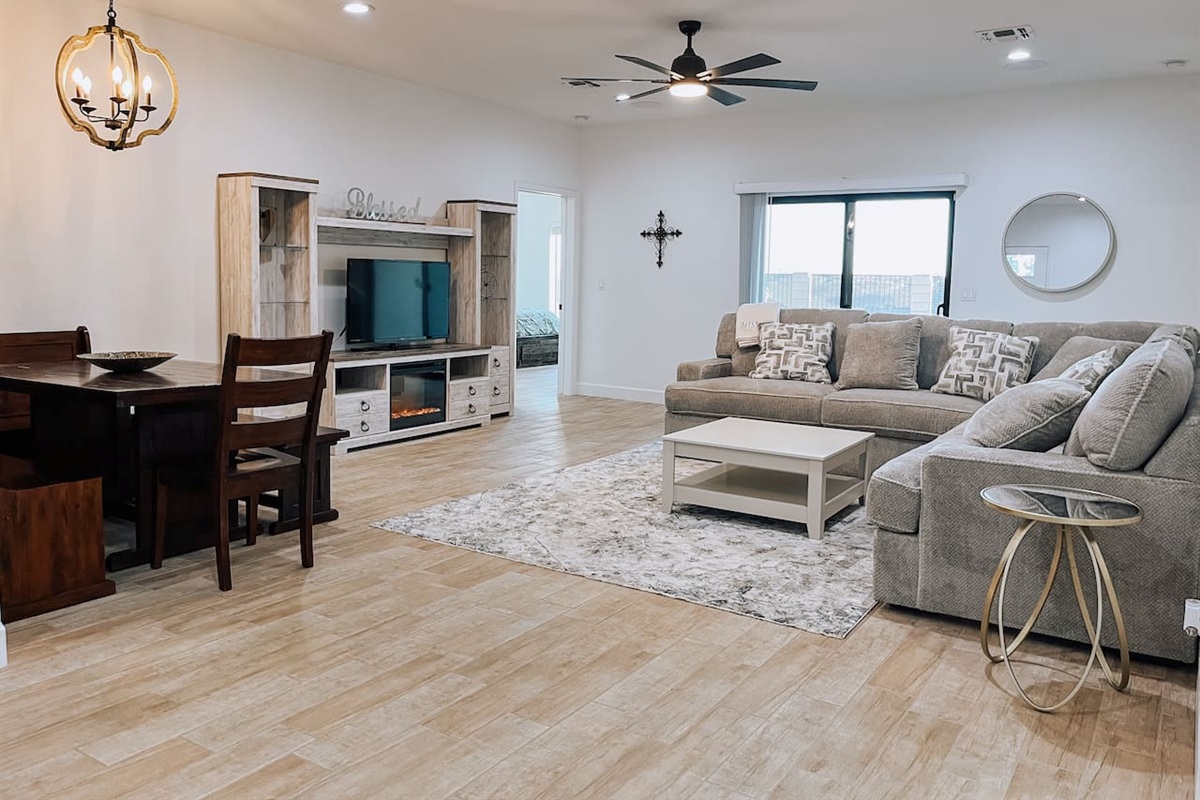 Bright and spacious living space area featuring a large sectional and entertainment center