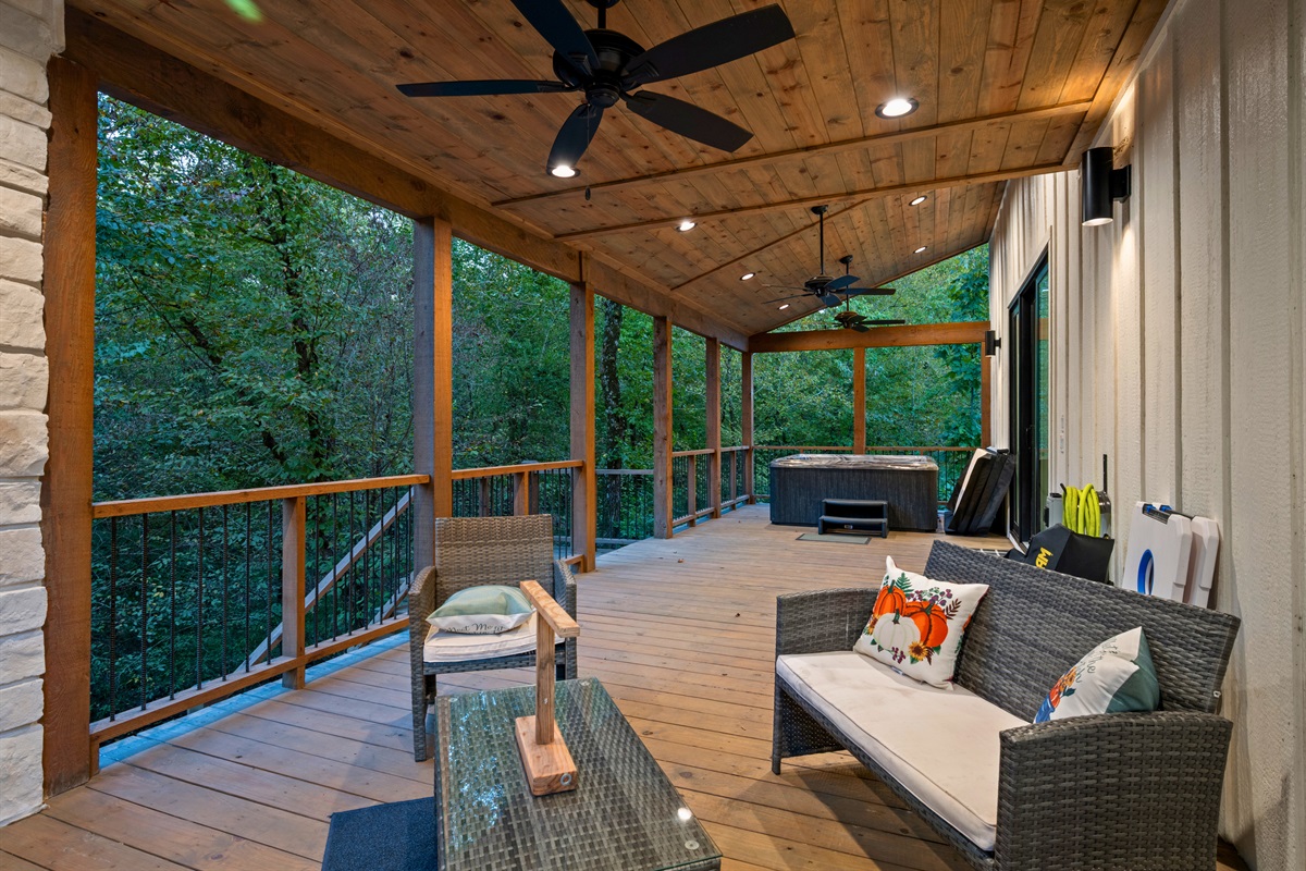 Another angle of the spacious covered deck shows plenty of seating and a welcoming spot to gather with friends and family while enjoying the forest views.
