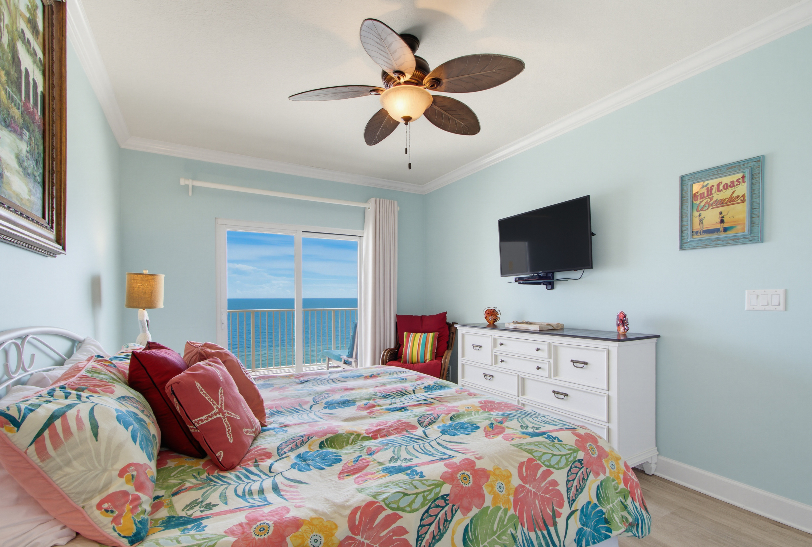 Primary king bedroom with Gulf views, balcony access, and a wall-mounted TV.