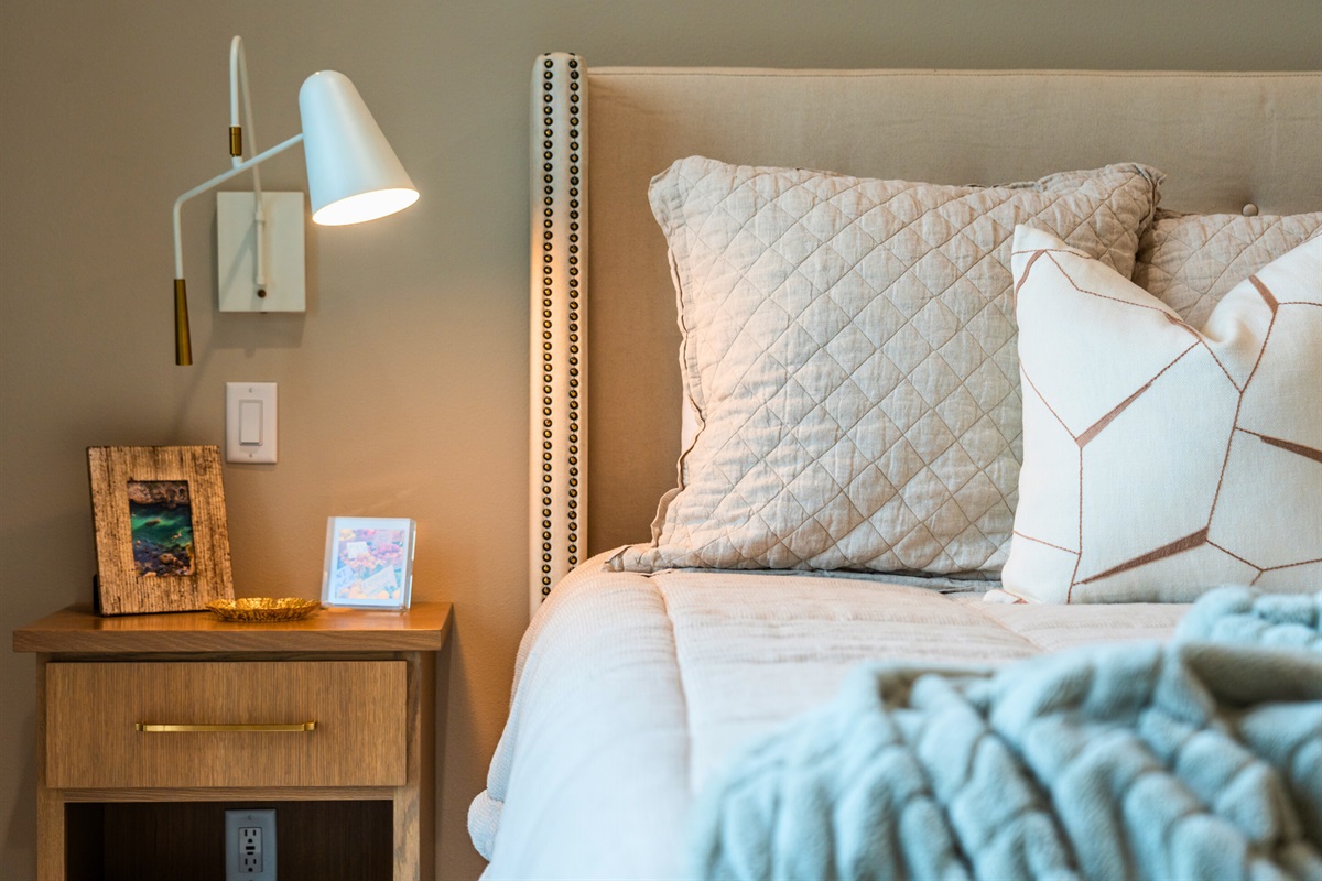 This elegant bedside setup features a stylish lamp and soft, inviting pillows, creating a perfect spot to relax.