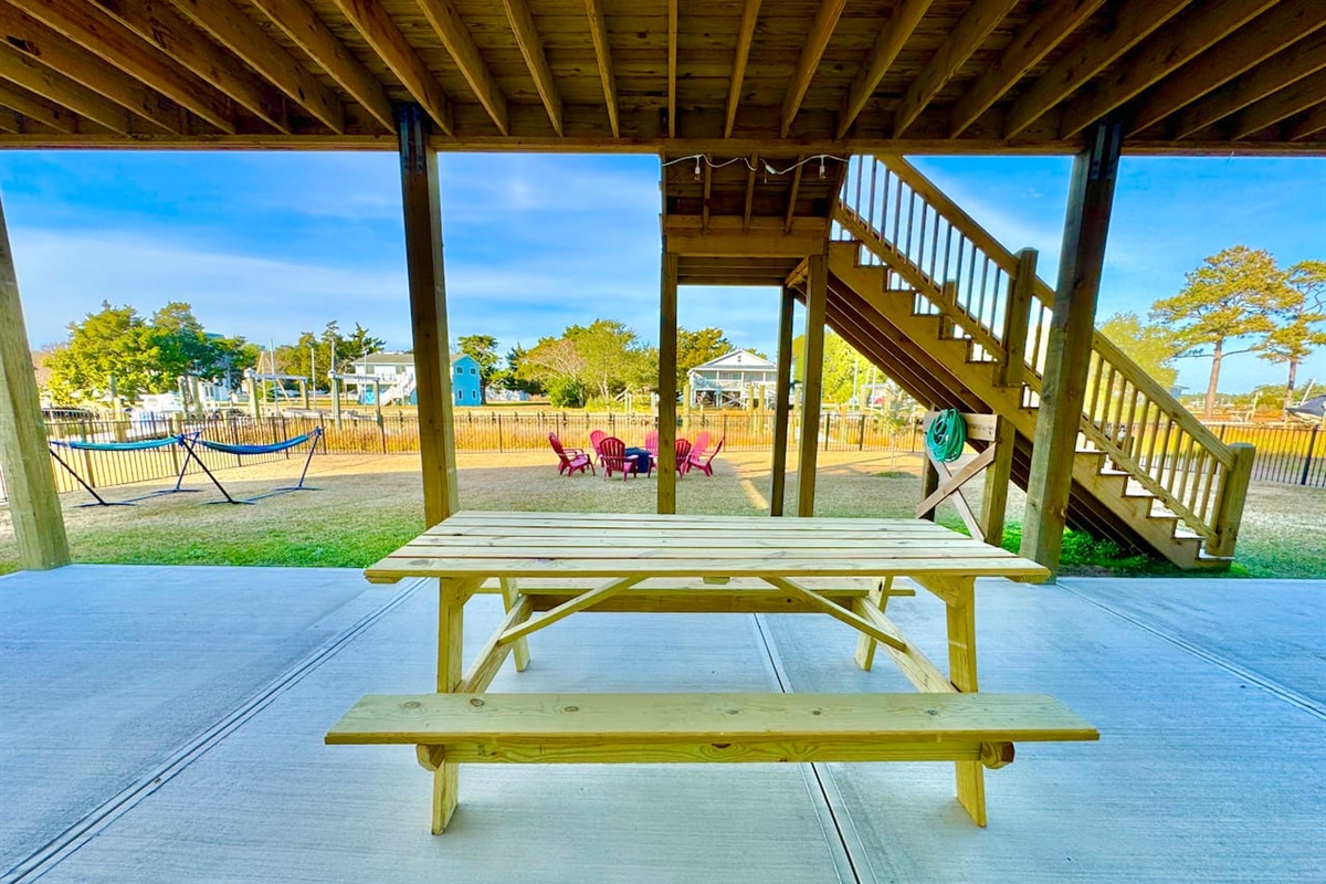 Private backyard dock with boat lift and fillet table, fenced-in backyard, fire pit with Adirondack chairs, hammocks, propane grill, picnic table, outdoor shower, expansive waterfront back deck with table and seating, neighborhood boat ramp and dock