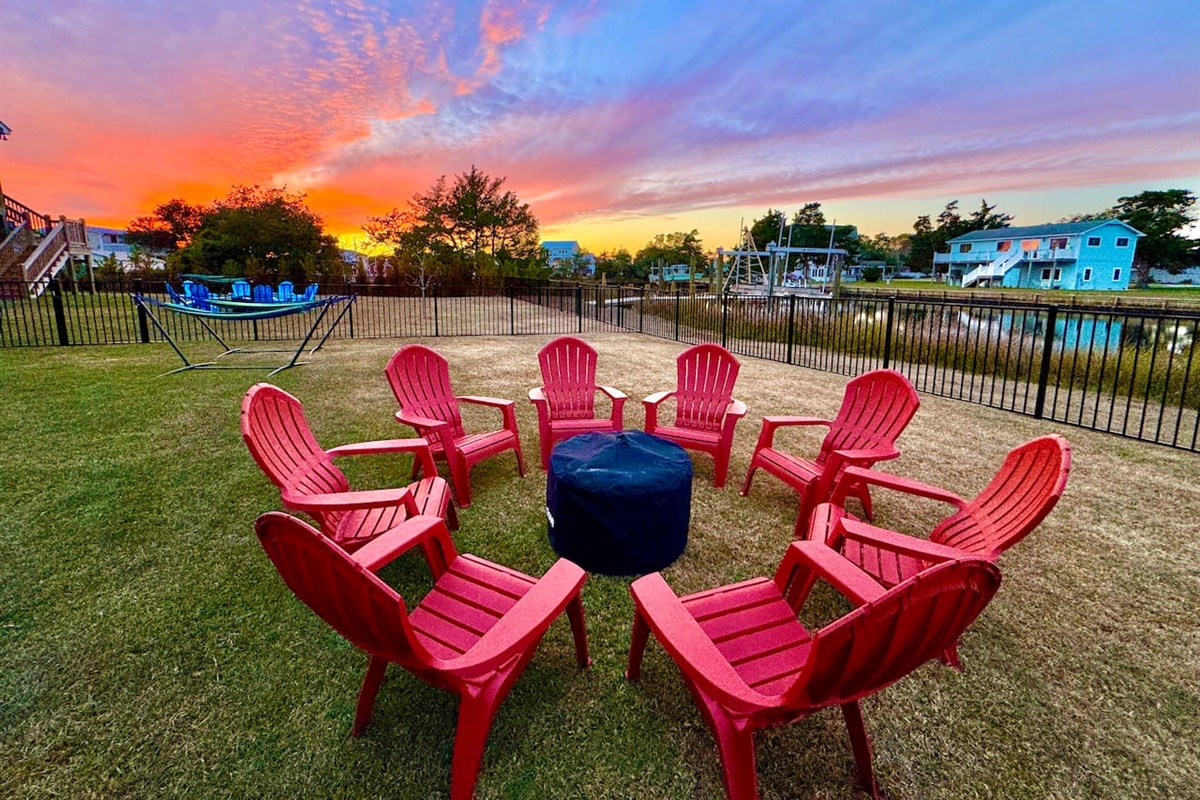 Private backyard dock with boat lift and fillet table, fenced-in backyard, fire pit with Adirondack chairs, hammocks, propane grill, picnic table, outdoor shower, expansive waterfront back deck with table and seating, neighborhood boat ramp and dock