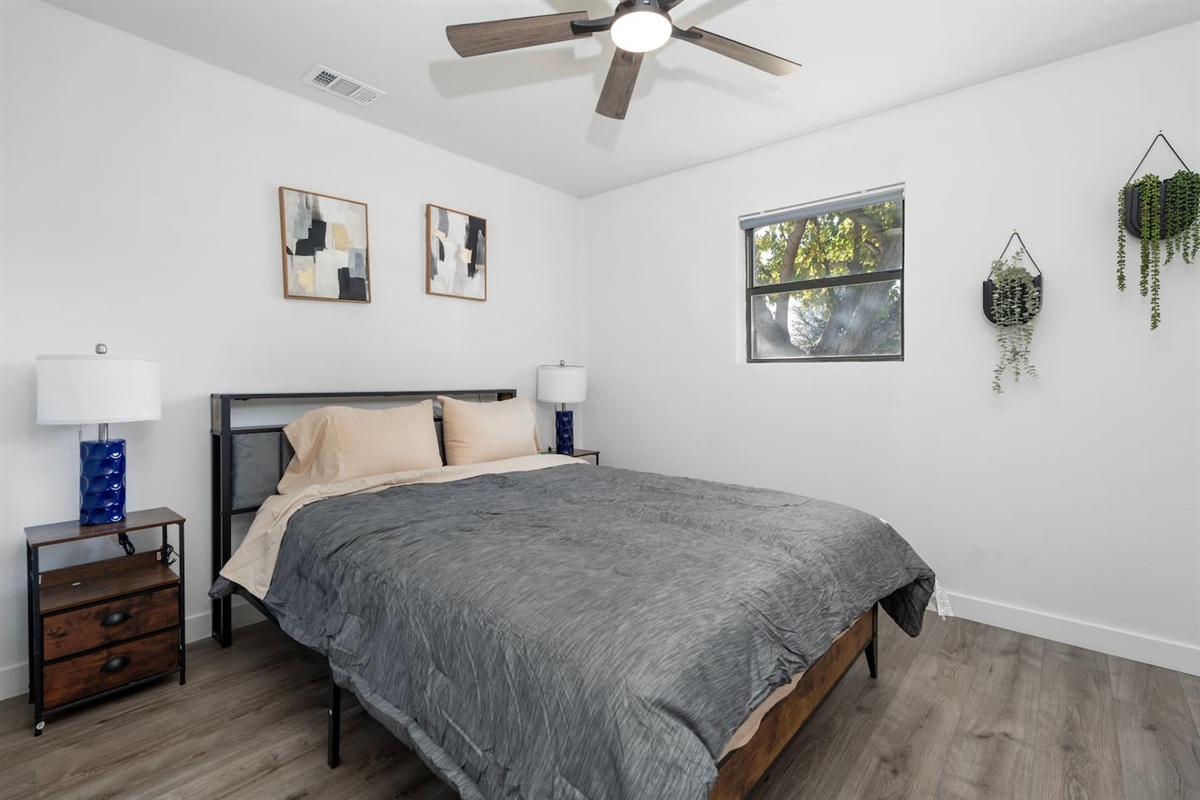 A calm and comfortable room featuring a queen bed, ceiling fan, and crisp bed linens. Ideal for a restful night after enjoying Grand Prairie and Greater DFW!