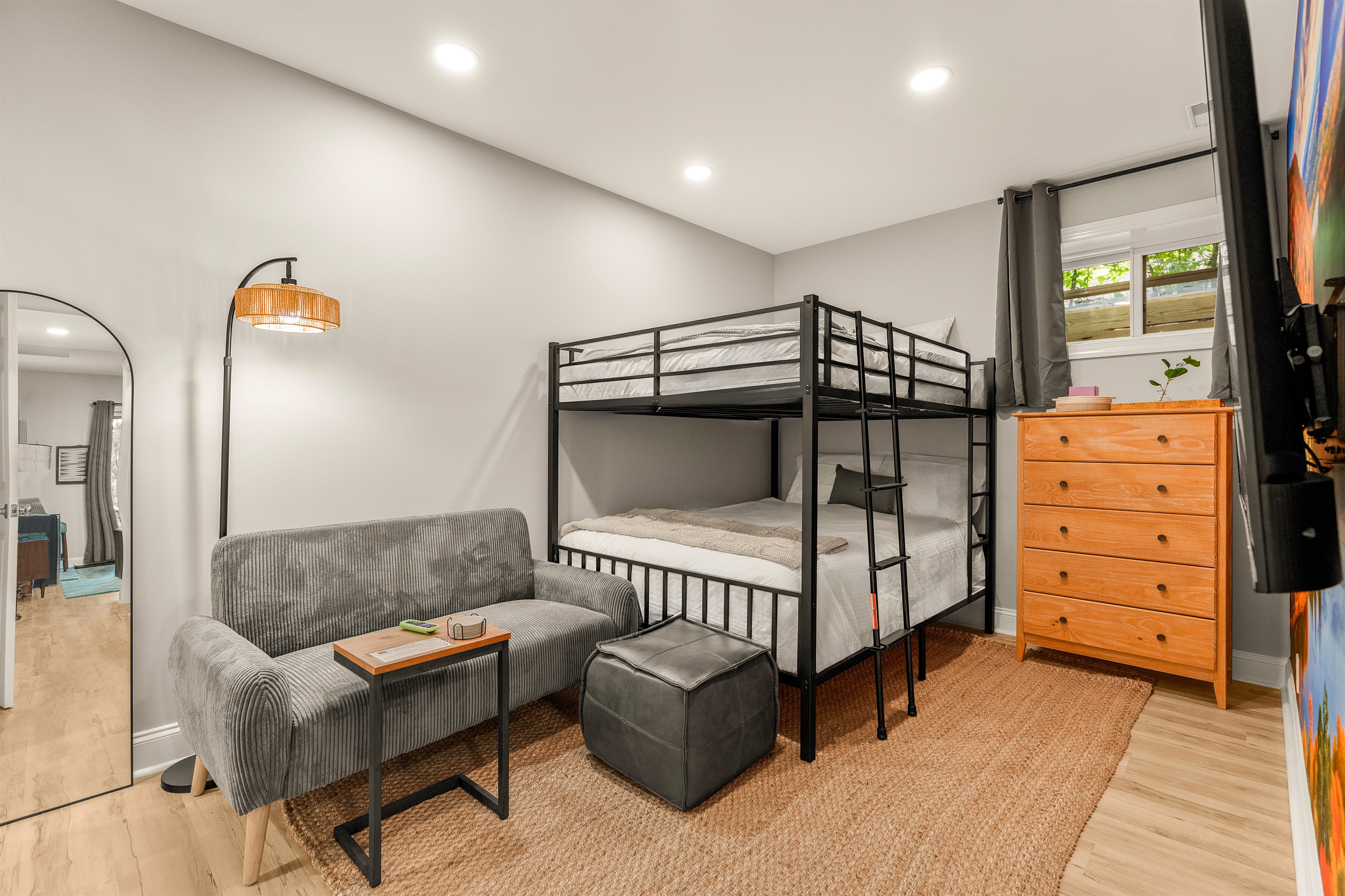 Colorful, cozy, and cleverly designed—this queen bunk room offers playful charm, a plush loveseat with ottoman, and all the essentials for movie nights, reading nooks, or winding down in style