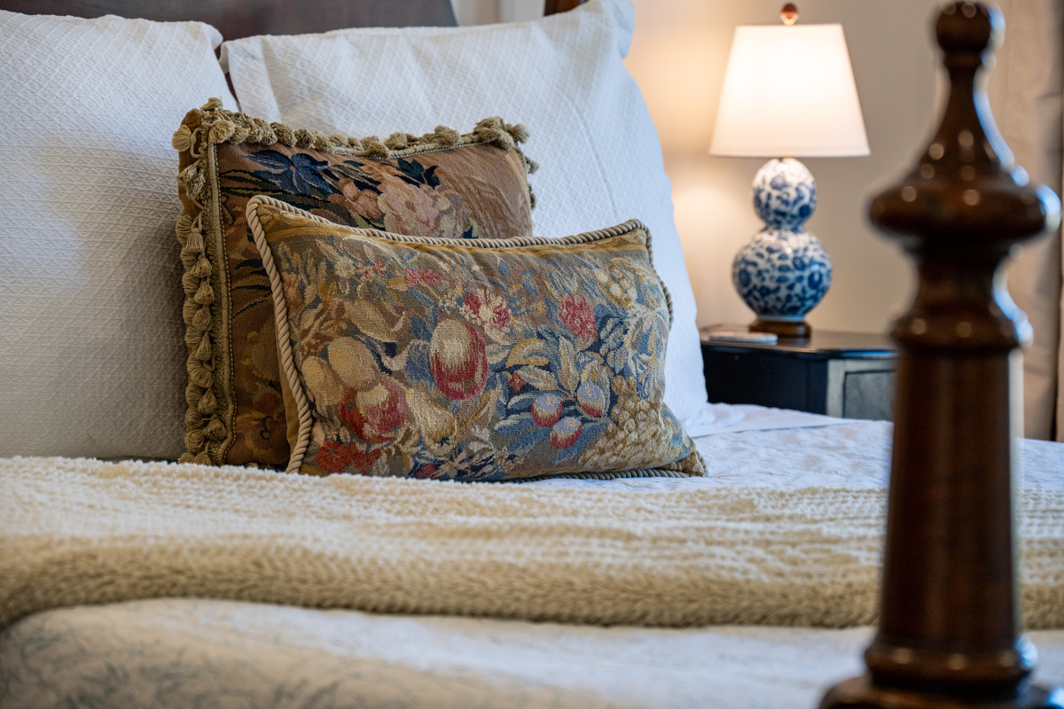 Layered textiles, elegant accent pillows, and warm bedside lighting bring a sophisticated and inviting touch to the bedroom.