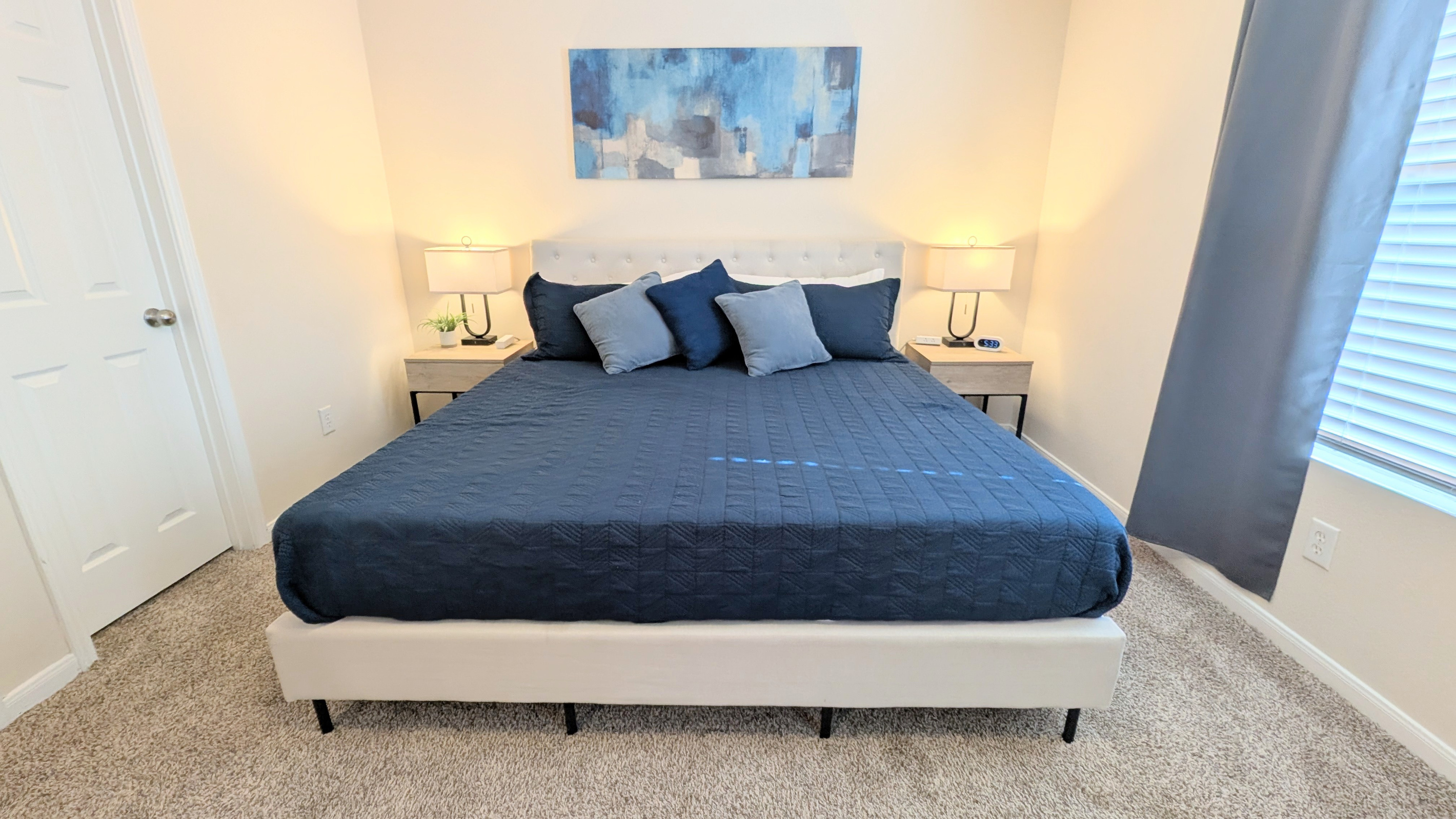 Oversized Primary suite includes a large walk-in closet, ceiling fan, cozy bedding, blackout curtains, a Roku TV, and dedicated workspace. Bedside tables have storage, an alarm clock, and easy access to charging ports.