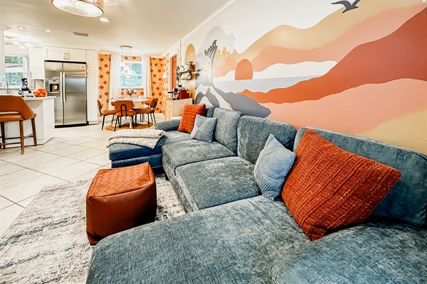 Living Room with Couch, 65" Roku TV, Indoor Electric LED Fire Place, Fandelier & Local Artist Mural