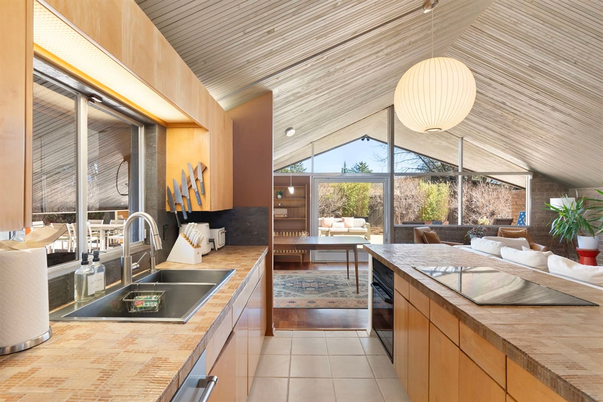 Modern kitchen with warm wood cabinetry and stunning views into the open living space.