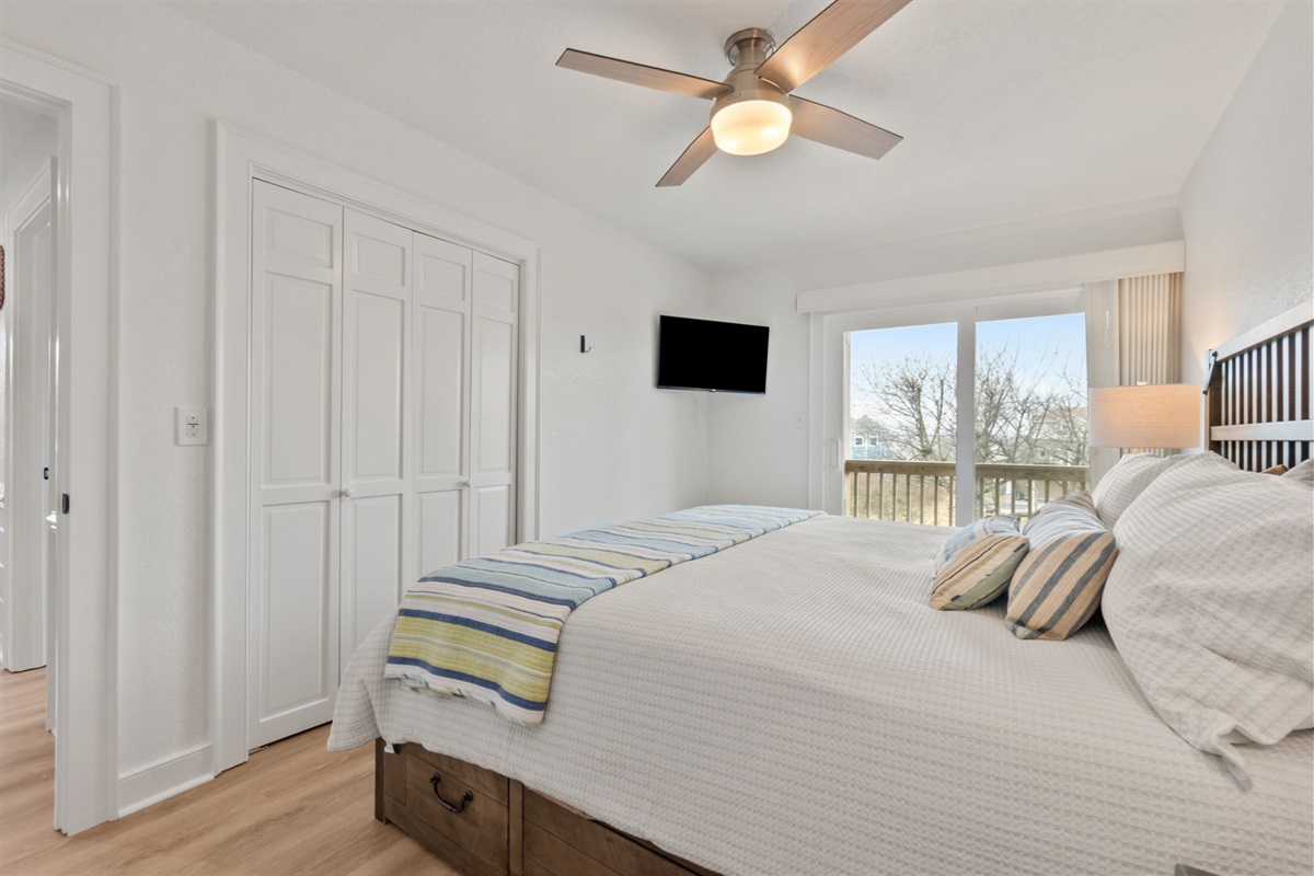 Comfortable queen bedroom with TV, closet space, and a clean layout.