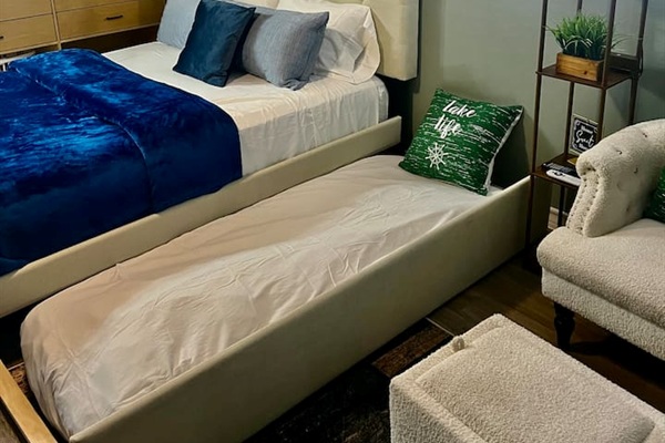 Queen bed with a twin pull-out underneath, plus a chair and ottoman for relaxing.
