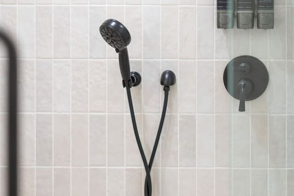 Handheld shower with mounted shampoo, conditioner, and body wash dispensers.